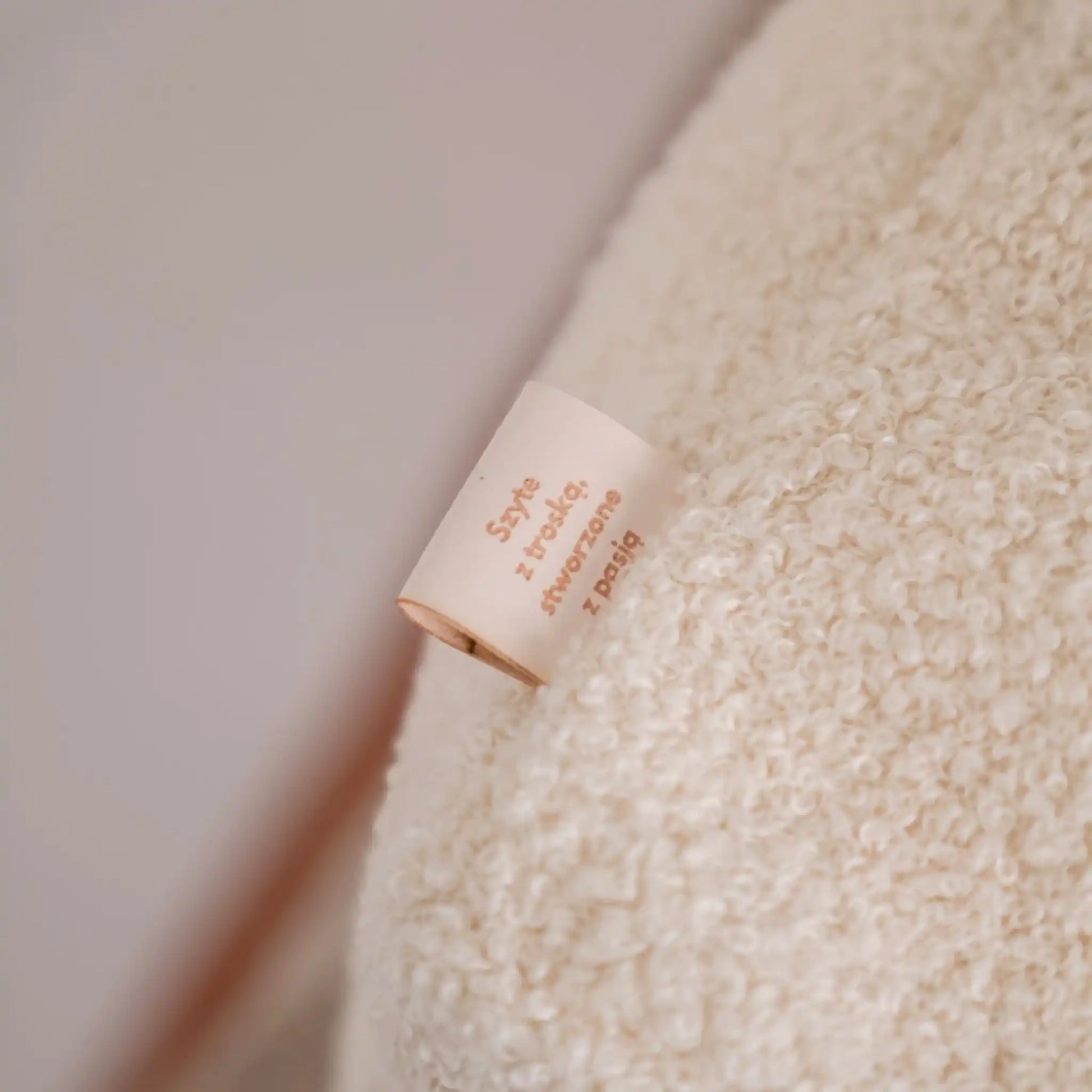 Detal na metkę w legowisku dla psa, tkanina boucle, kolor chałwa (kremowy). Nowoczesna, wysokiej jakości tkanina boucle z certyfikatami bezpieczeństwa.