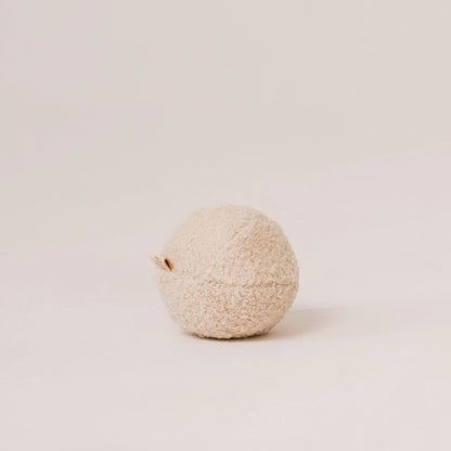 Miękka piłka dla psa z tkaniny boucle w kolorze chałwa (kremowy). Widoczna metka z logo. Jasne, czyste tło.